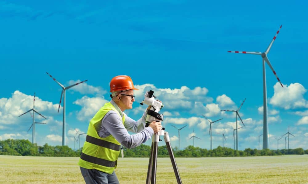 Land surveyor measuring farmland near wind turbines in Iowa before a proposed wind lease